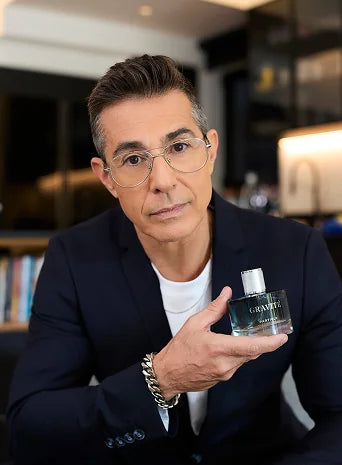 Man wearing glasses holding Gravité men’s fragrance
