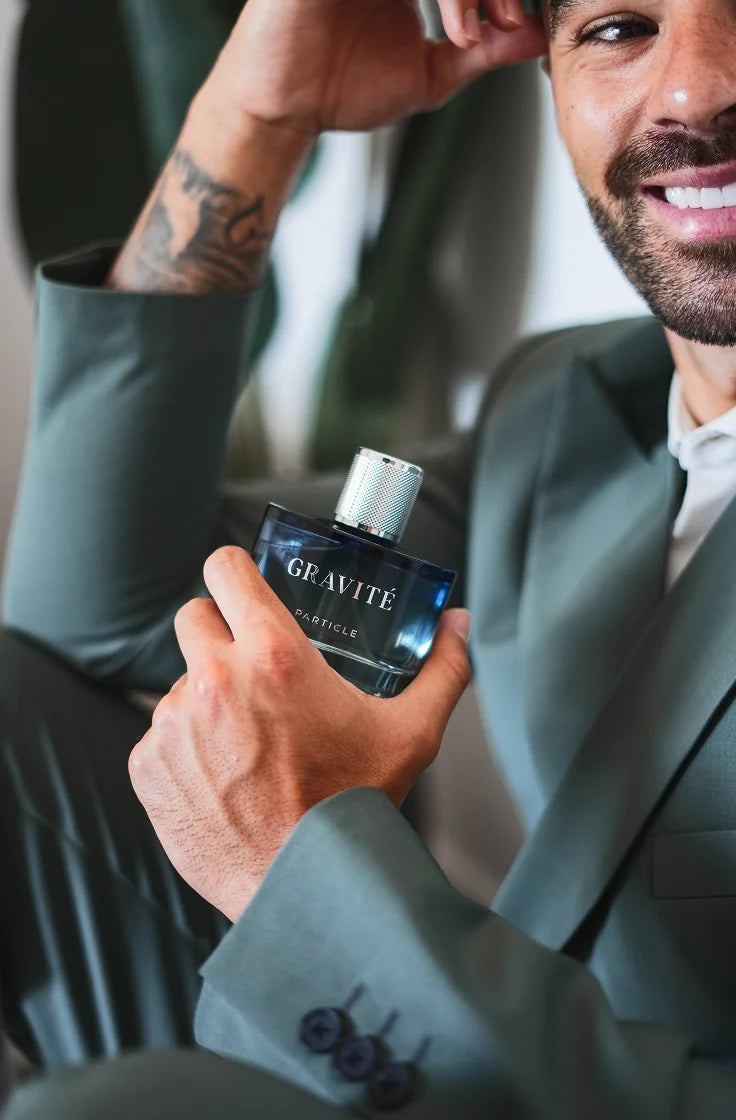 Smiling man holding Gravité men’s fragrance