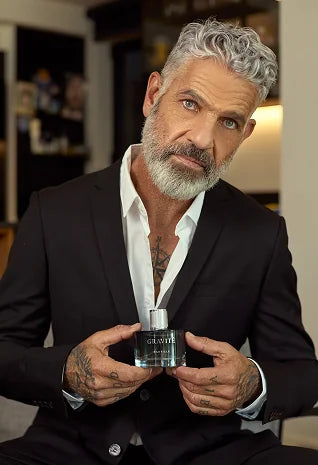 Silver-haired man holding Gravité men’s fragrance